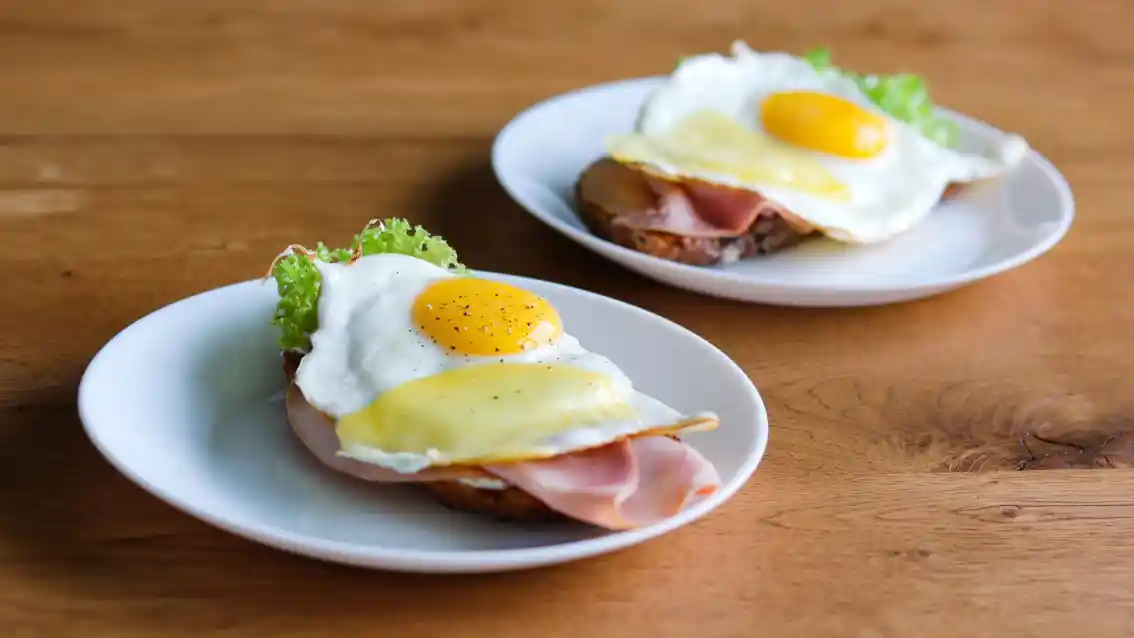 Open warm sandwich with ham, cheese, lettuce and fried egg served for breakfast